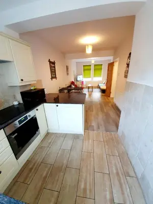 a kitchen with white cabinets and a wooden floor at Beautiful 3 Bedroom House at the Sea Front - Amazing Location in Southend-on-Sea
