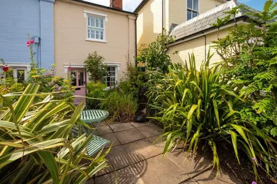 a garden with two chairs and plants in front of a house at Bloom Cottage in Aldeburgh