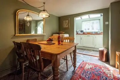 a dining room with a wooden table and a mirror at Bloom Cottage in Aldeburgh