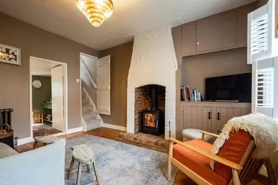 a living room with a fireplace and a tv at Bloom Cottage in Aldeburgh