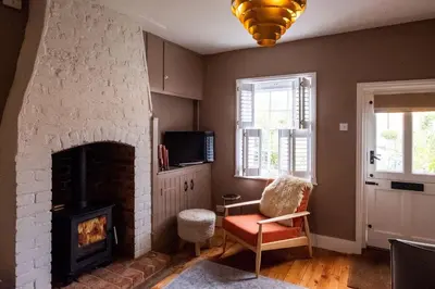 a living room with a brick fireplace and a chair at Bloom Cottage in Aldeburgh