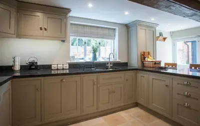 a kitchen with white cabinets and black counter tops at Westgate Lodge at Dedham in Dedham