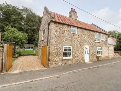 an old stone building with a red roof on a street at Garden House in Thetford