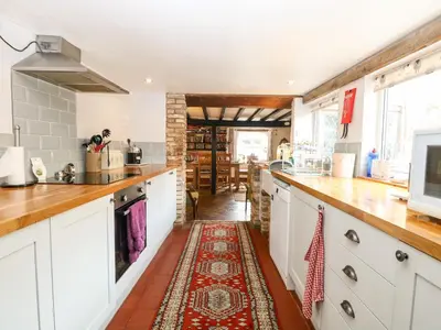 a kitchen with white cabinets and a rug on the floor at Garden House in Thetford