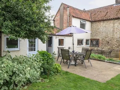 a patio with a table and chairs and an umbrella at Garden House in Thetford