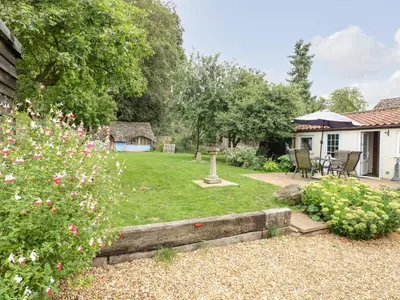 a garden with a table and chairs and flowers at Garden House in Thetford