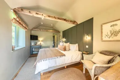 a bedroom with a large bed and a chair at Church Farm B&B Suffolk in Great Welnetham