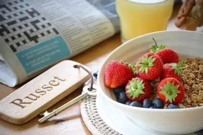 a bowl of strawberries and blueberries next to a book at Church Farm B&B Suffolk in Great Welnetham