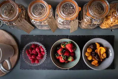 a table topped with bowls of strawberries and fruit at Church Farm B&B Suffolk in Great Welnetham