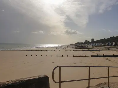 a beach with a few people standing on the sand at Sea View Cottage in Frinton-on-Sea