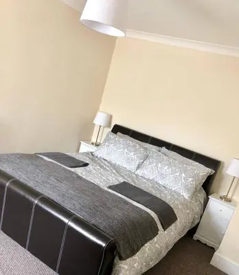 a bed in a bedroom with two night stands and two lamps at AC Lounge 115 in Rochford