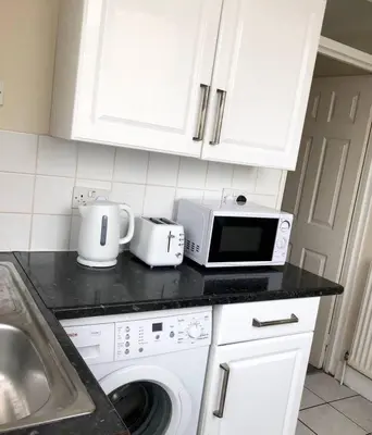 a kitchen counter with a microwave and a sink at AC Lounge 115 in Rochford