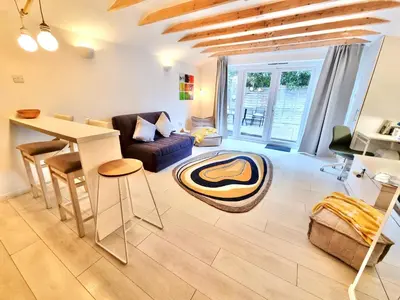 a living room with a table and a couch at Modern self contained tiny home with patio in Loughton