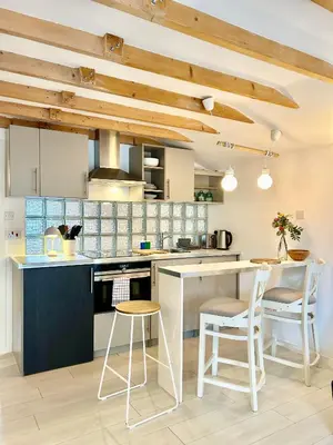 a kitchen with wooden ceilings and a kitchen island with stools at Modern self contained tiny home with patio in Loughton
