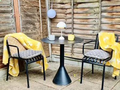 two chairs and a table with a lamp on it at Modern self contained tiny home with patio in Loughton