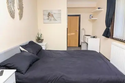 a bedroom with a large bed with a blue blanket at Pet Friendly Home in Chelmsford-Hot Tub-Sleeps 6 in Latchingdon and Snoreham