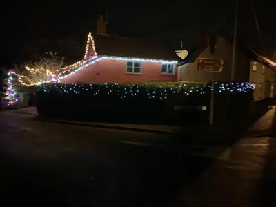 a house decorated with christmas lights on a street at Myrtle cottage in Dickleburgh