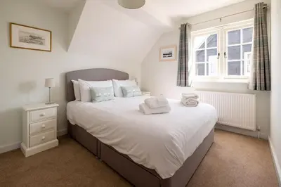 a bedroom with a large white bed with a window at 5 The Haven in Thorpeness