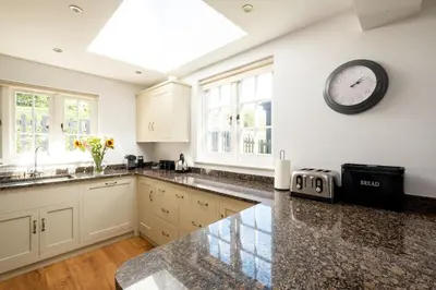 a kitchen with a clock on the wall and a counter at 5 The Haven in Thorpeness
