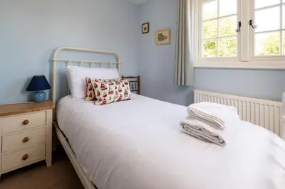a bedroom with a bed with white sheets and a window at 5 The Haven in Thorpeness