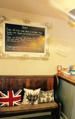 a sign on a wall above a bench with pillows at The British Queen, Meldreth in Meldreth