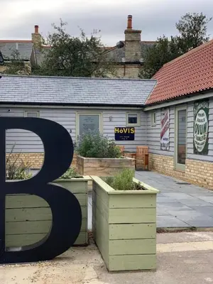 a large sign in front of a building with plants at The British Queen, Meldreth in Meldreth