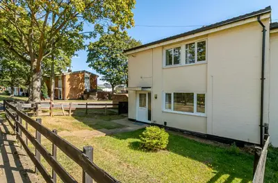 a white house with a fence and a tree at Hillcrest Lodge in Stevenage