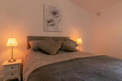 a bedroom with a large bed with two lamps at Hillcrest Lodge in Stevenage