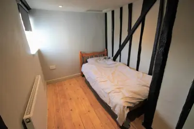 a bed in a room with a wooden floor at Best located and beautifully renovated cottage in Diss