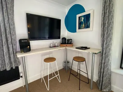 a room with a desk with a tv and two stools at CopperBeech Bed and Breakfast in Yoxford