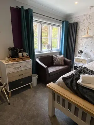 a bedroom with a bed and a couch and a chair at CopperBeech Bed and Breakfast in Yoxford