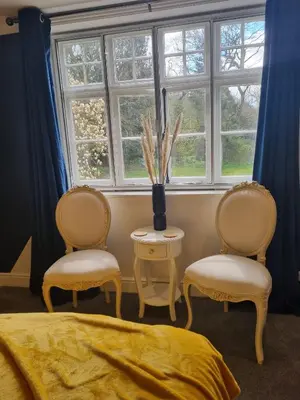 a bedroom with two chairs and a table and a window at CopperBeech Bed and Breakfast in Yoxford