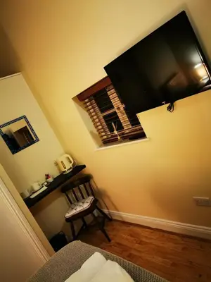 a room with a television on the wall and a chair at The Cavendish Five Bells in Cavendish