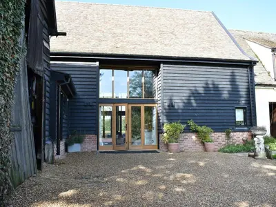 a blue house with a glass door and some plants at Ivy Todd Barn in Ashdon