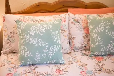 a bed with four pillows on it with at Cobweb Cottage Studios in Spooner Row