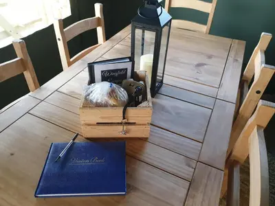 a wooden table with a candle and a box with a book at Wingfield Escapes in Diss