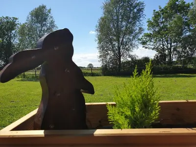 a statue of a person holding an umbrella in a garden at Wingfield Escapes in Diss