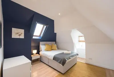 a bedroom with a bed and a blue wall at Colchester Town Duplex Apartment in Colchester