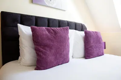 two purple pillows sitting on top of a bed at Velvet 2-bedroom apartment, Clockhouse, Hoddesdon in Hoddesdon