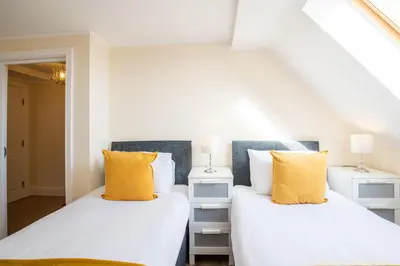 two beds in a room with white and yellow pillows at Velvet 2-bedroom apartment, Clockhouse, Hoddesdon in Hoddesdon