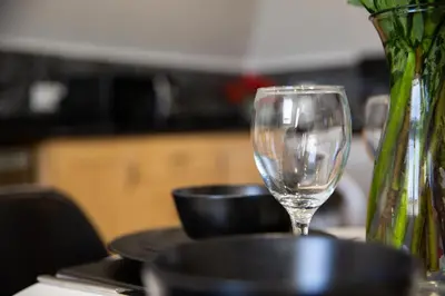 a wine glass sitting on a table next to a vase at Velvet 2-bedroom apartment, Clockhouse, Hoddesdon in Hoddesdon