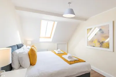 a bedroom with a bed with white sheets and a window at Velvet 2-bedroom apartment, Clockhouse, Hoddesdon in Hoddesdon