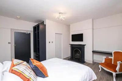 a bedroom with a bed and a chair and a fireplace at Pages Hotel and Guesthouse in Harlow