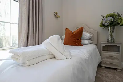 a bedroom with white towels on a bed with a vase of flowers at Pages Hotel and Guesthouse in Harlow