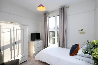 a bedroom with a bed and a tv and a window at Pages Hotel and Guesthouse in Harlow