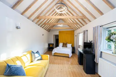 a living room with a yellow couch and a bed at Pages Hotel and Guesthouse in Harlow