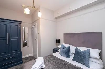 a bedroom with a large bed with blue pillows at Pages Hotel and Guesthouse in Harlow
