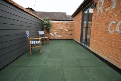 a patio with two chairs and a table and a brick wall at Spacious Apartment with Roof Terrace, near The Waterfront, Ipswich in Ipswich