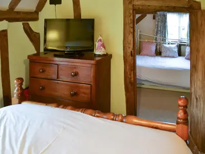 a bedroom with a television and a dresser with a mirror at Tattlepot Farmhouse in Tivetshall Saint Margaret