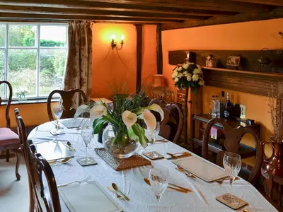 a dining room with a table with a vase of flowers at Tattlepot Farmhouse in Tivetshall Saint Margaret